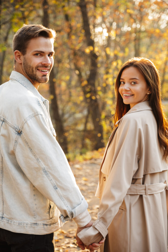 Beautiful smiling young couple walking in the autumn park